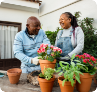 A senior couple tend to potted flowers outside their home.  